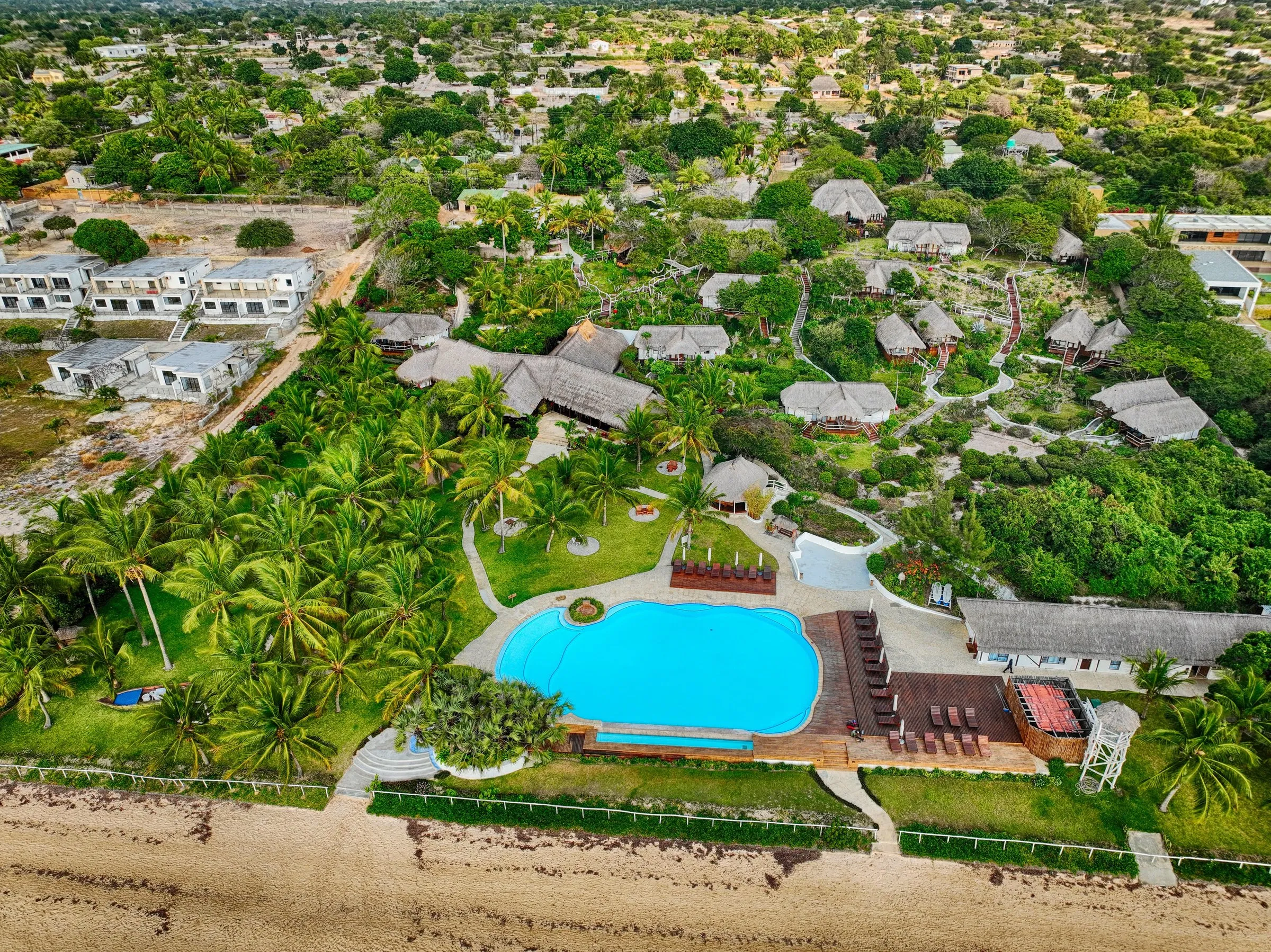 Aerial view of Vilanculos Beach Lodge — thatched chalets, pool and palm gardens behind the beach