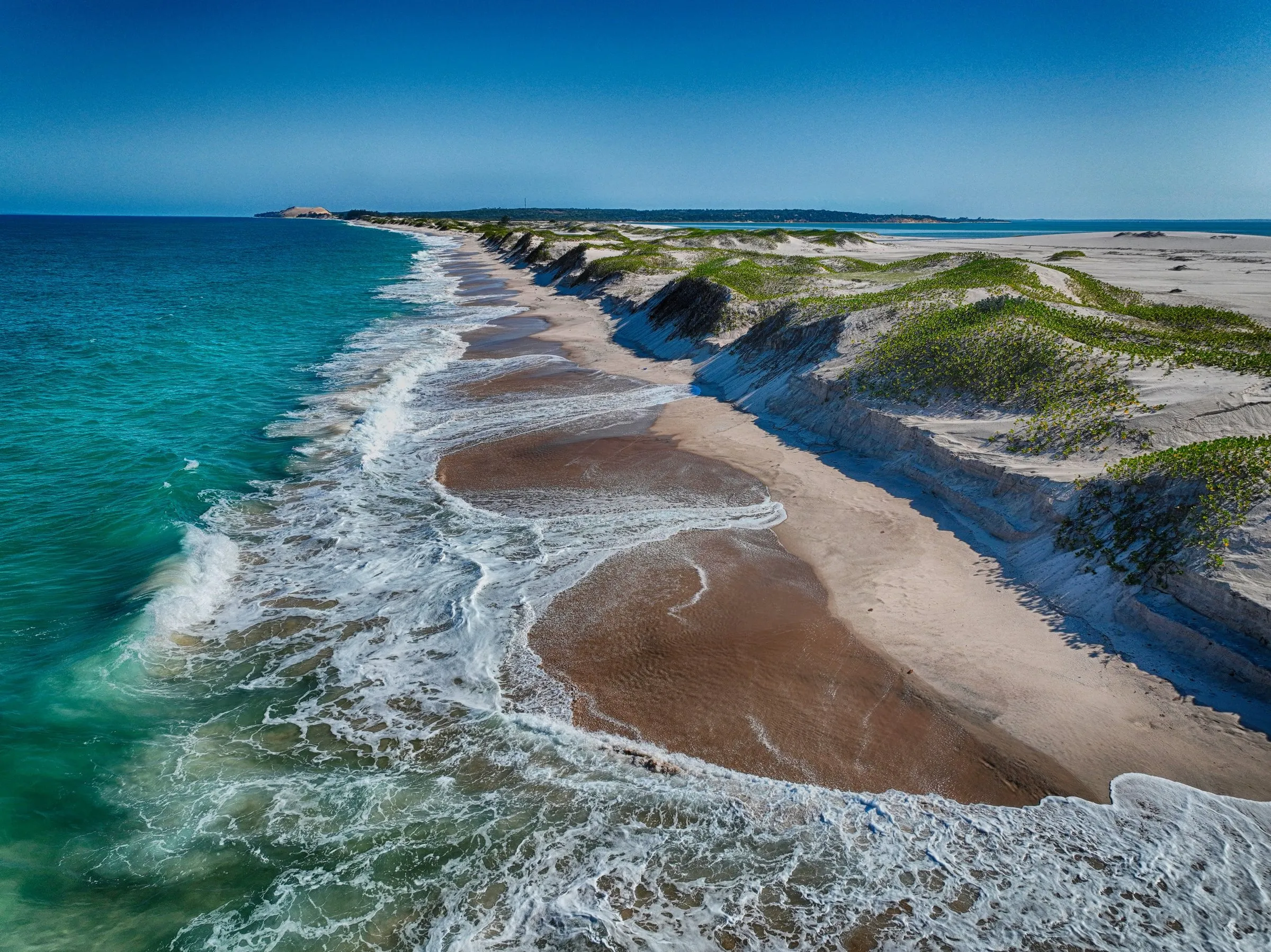 Turquoise surf breaking on a dune-backed beach near Vilanculos